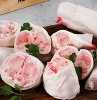 Multiple pieces of raw Beef Paya (trotters or feet) arranged on a platter, garnished with parsley.