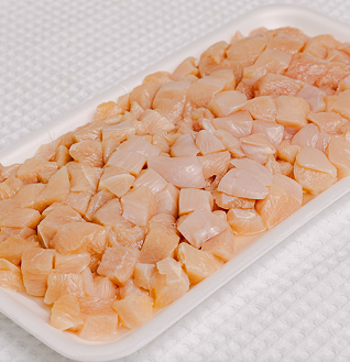 Large quantity of raw, diced Chicken Thai Chili cubes in a white styrofoam tray.