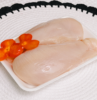 Two raw Chicken Breast fillets on a white tray, garnished with sliced red pepper.