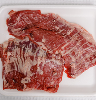Raw Beef Fatita (skirt steak or similar cut) laid flat on a white styrofoam tray.