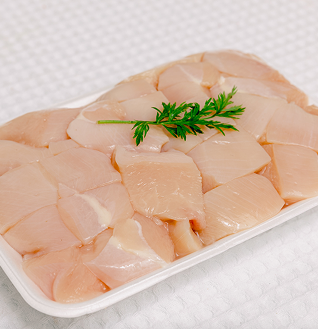 Raw Chicken Breast Boti cubes in a white tray, garnished with a sprig of fresh parsley.